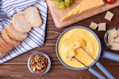 Photo of Flat lay composition with pot of cheese fondue and products on wooden table