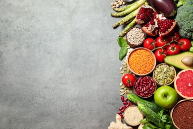 Photo of Fresh vegetables, fruits and seeds on grey table, flat lay. Space for text