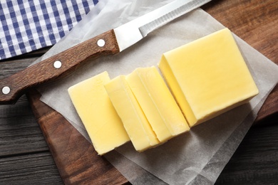 Photo of Wooden board with fresh butter and knife on table, top view