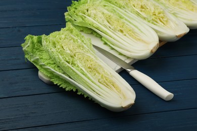 Photo of Cut fresh ripe Chinese cabbages on blue wooden table