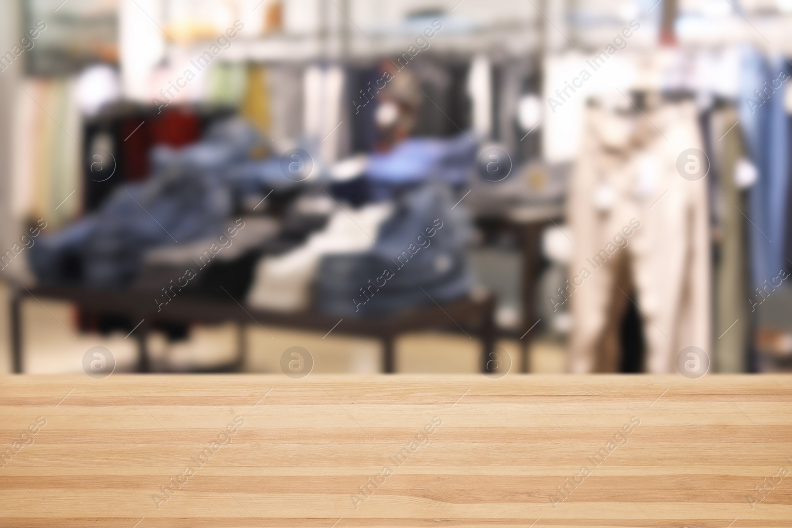 Image of Empty wooden table and blurred view of store with modern clothes