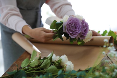 Photo of Florist making beautiful wedding bouquet at wooden table, closeup