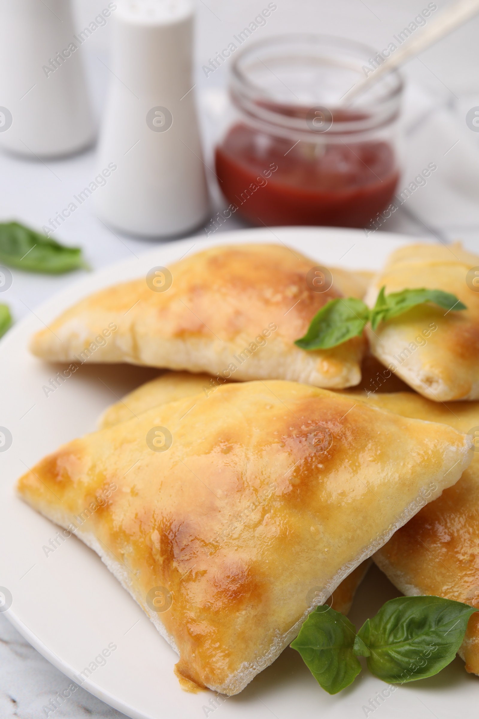 Photo of Delicious samosas and basil on white table, closeup