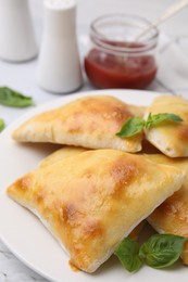 Delicious samosas and basil on white table, closeup