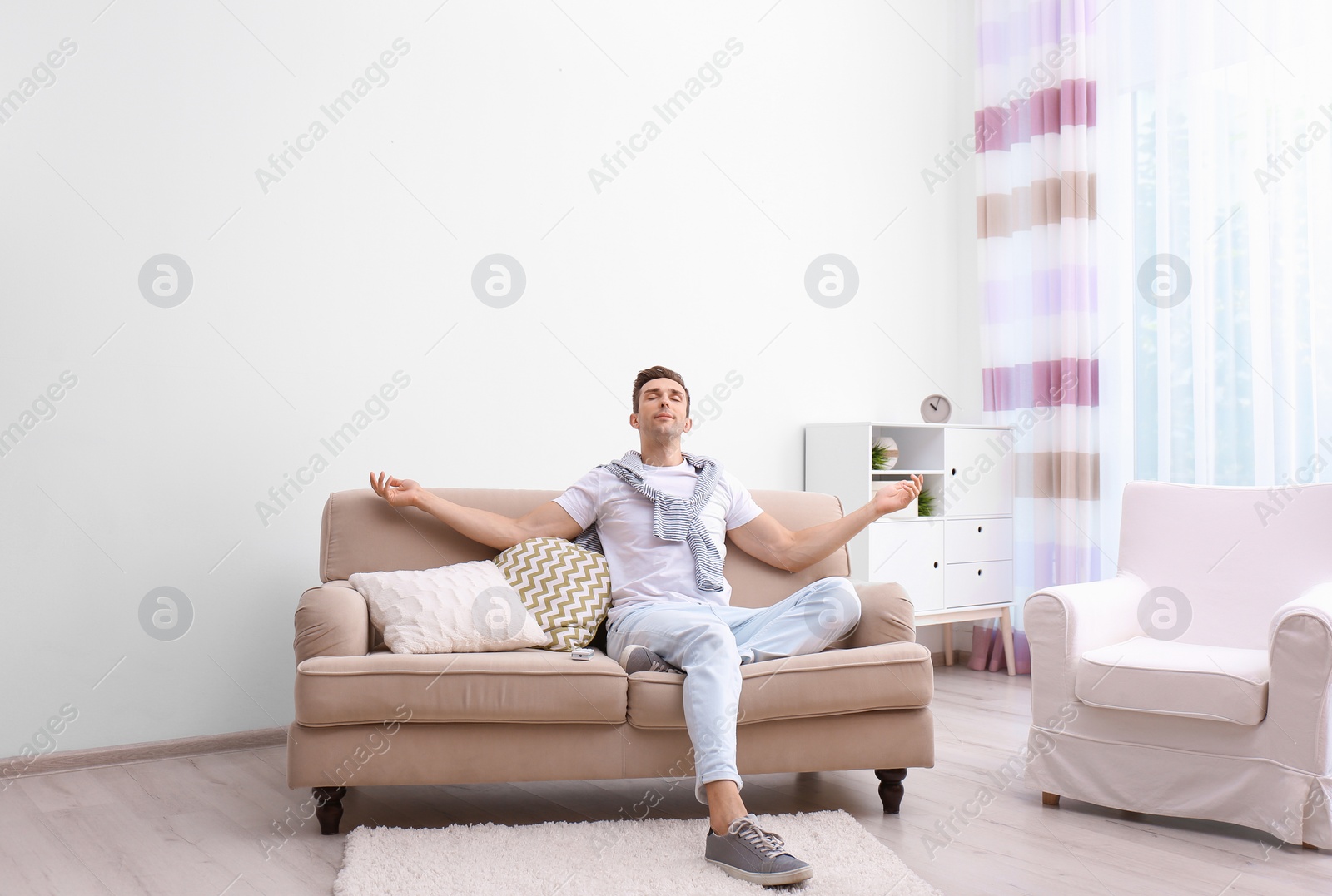 Photo of Happy young man sitting under air conditioner at home