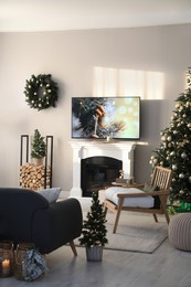 Photo of Modern TV set on light wall in room decorated for Christmas