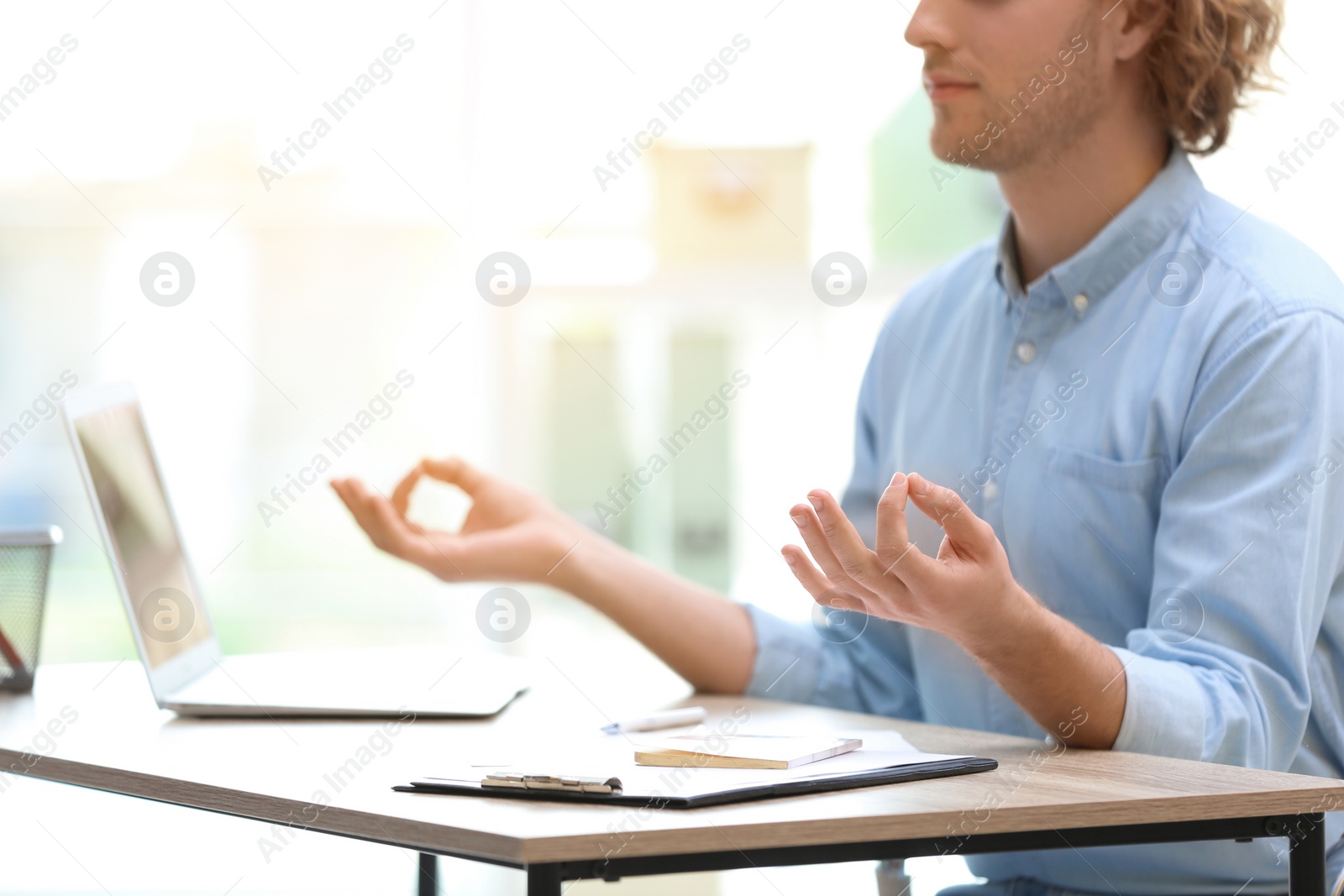 Photo of Young businessman meditating at table in office during break, closeup with space for text. Zen yoga