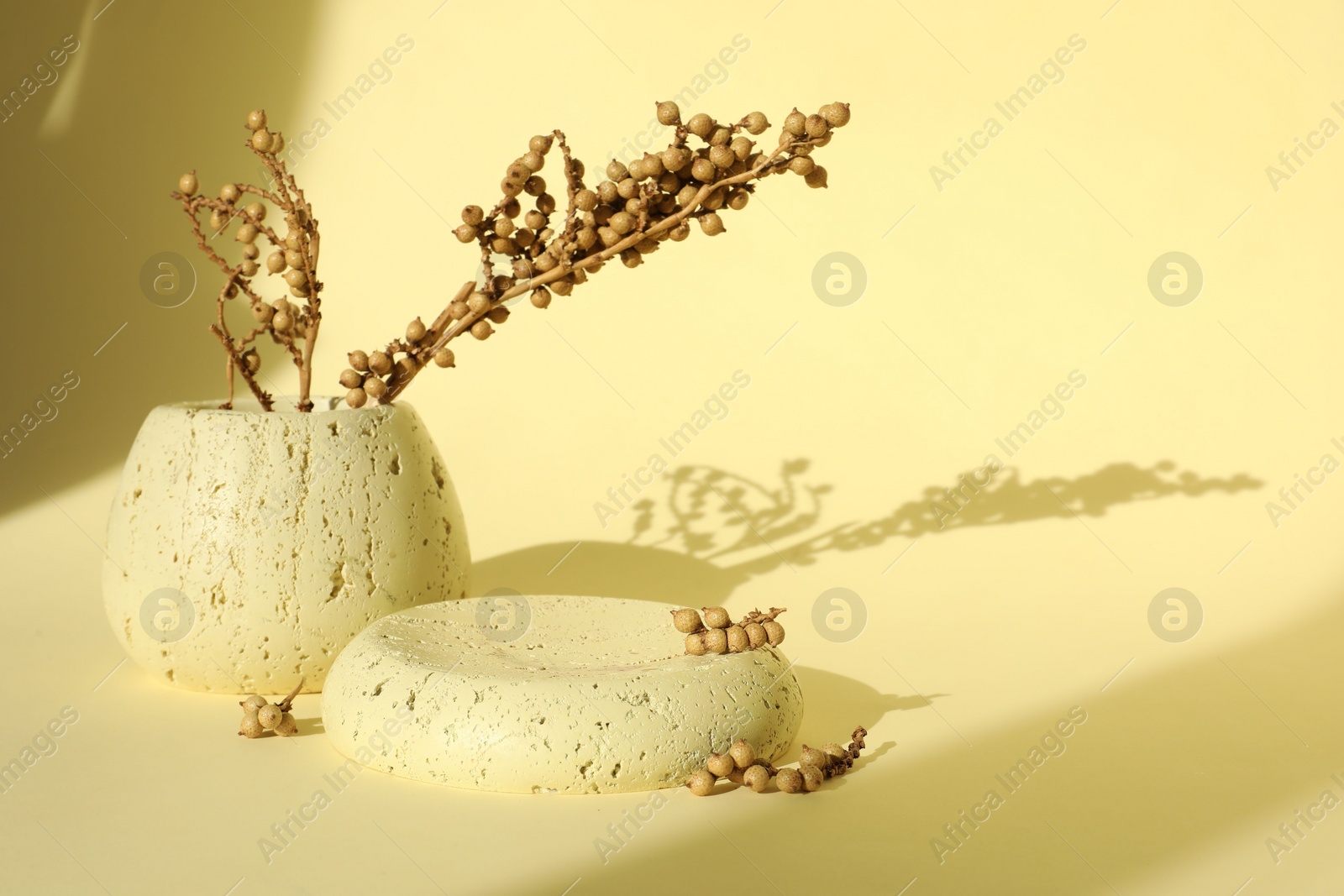 Photo of Presentation of product. Stone podium and vase with beautiful branches on yellow background. Space for text