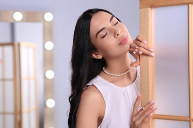 Photo of Young woman wearing elegant pearl jewelry indoors, space for text