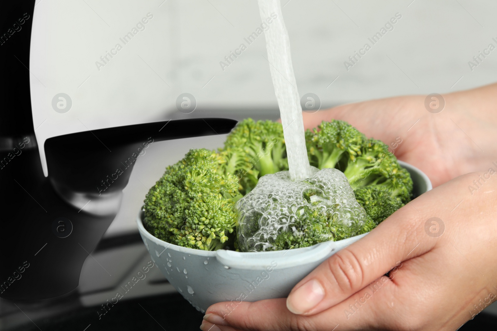 Photo of Woman washing fresh green broccoli in kitchen sink, closeup