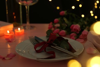 Photo of Place setting with roses and candles on pink wooden table, closeup. Romantic dinner