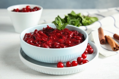 Bowl of tasty cranberry sauce with mint on table