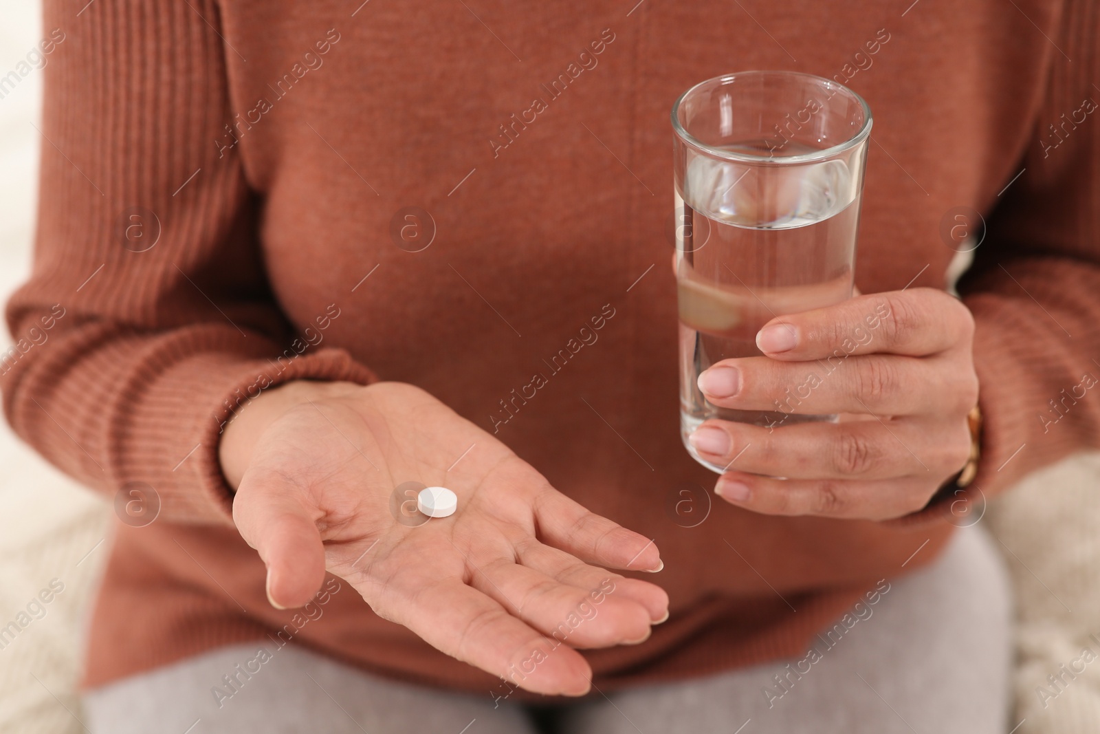Photo of Senior woman with pill and glass of water indoors, closeup