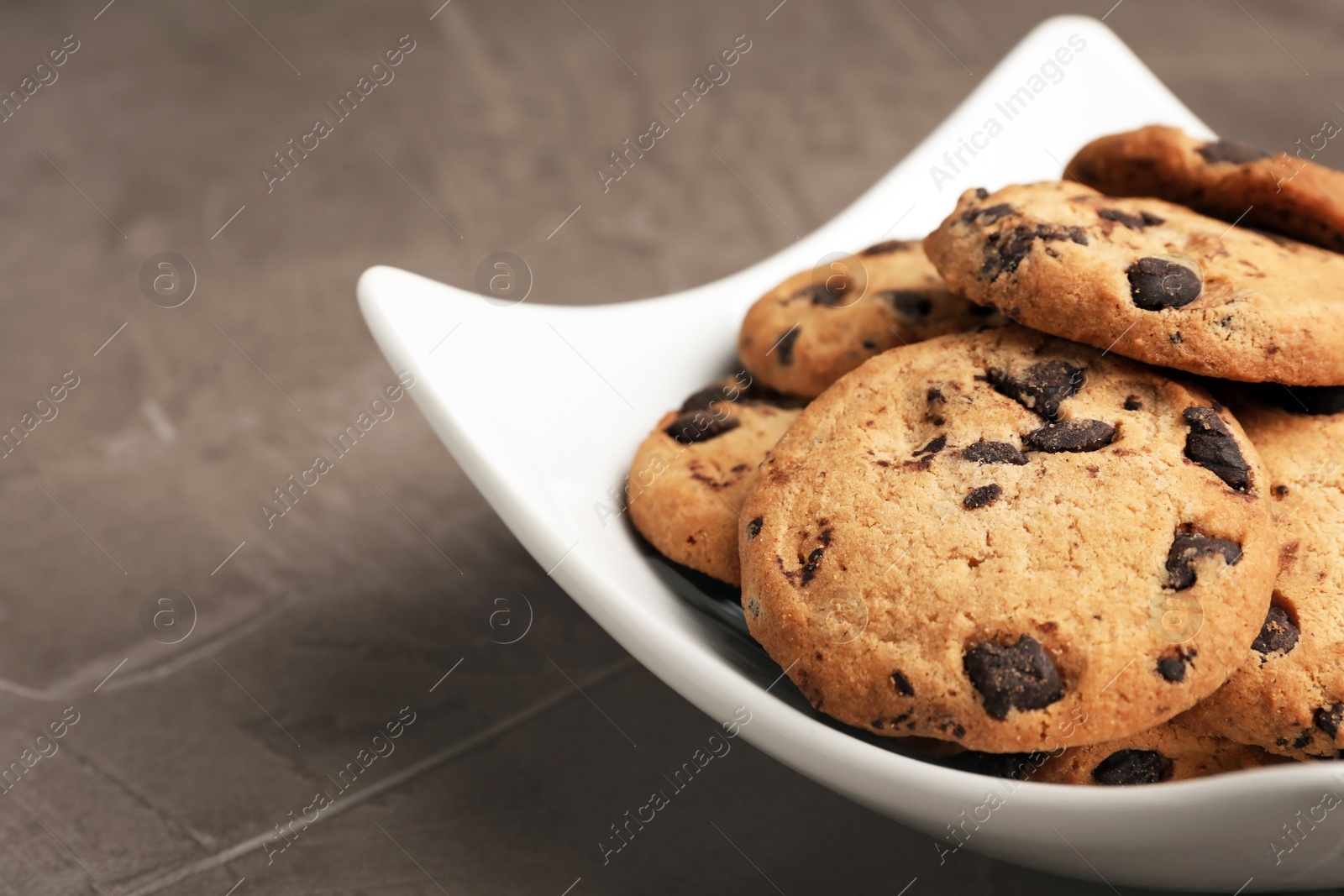 Photo of Plate with chocolate chip cookies on grey background, closeup