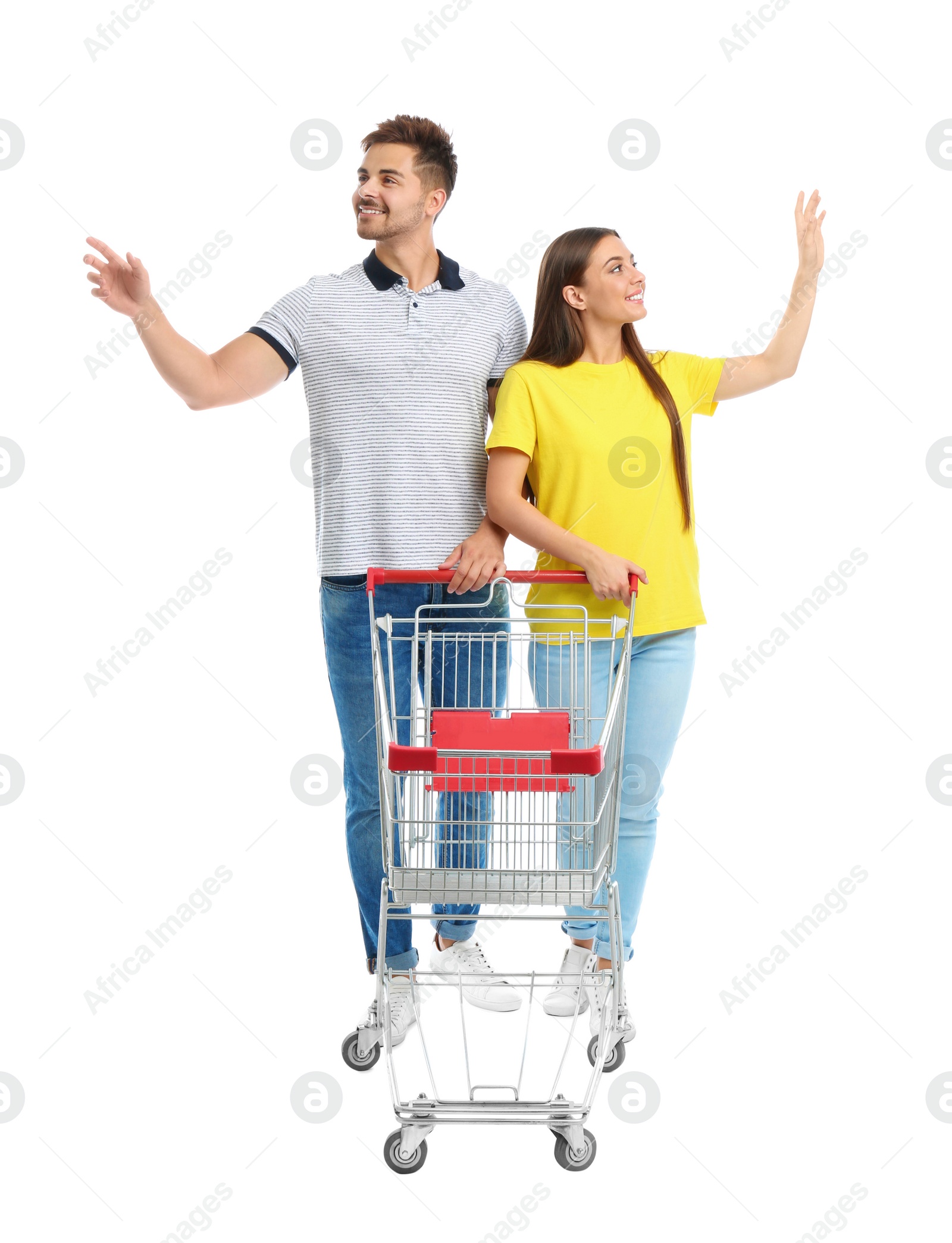 Photo of Young couple with empty shopping cart on white background