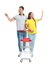 Young couple with empty shopping cart on white background