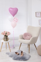 Photo of Beautiful roses on coffee table, comfortable armchair and air balloons in cozy room. Happy birthday