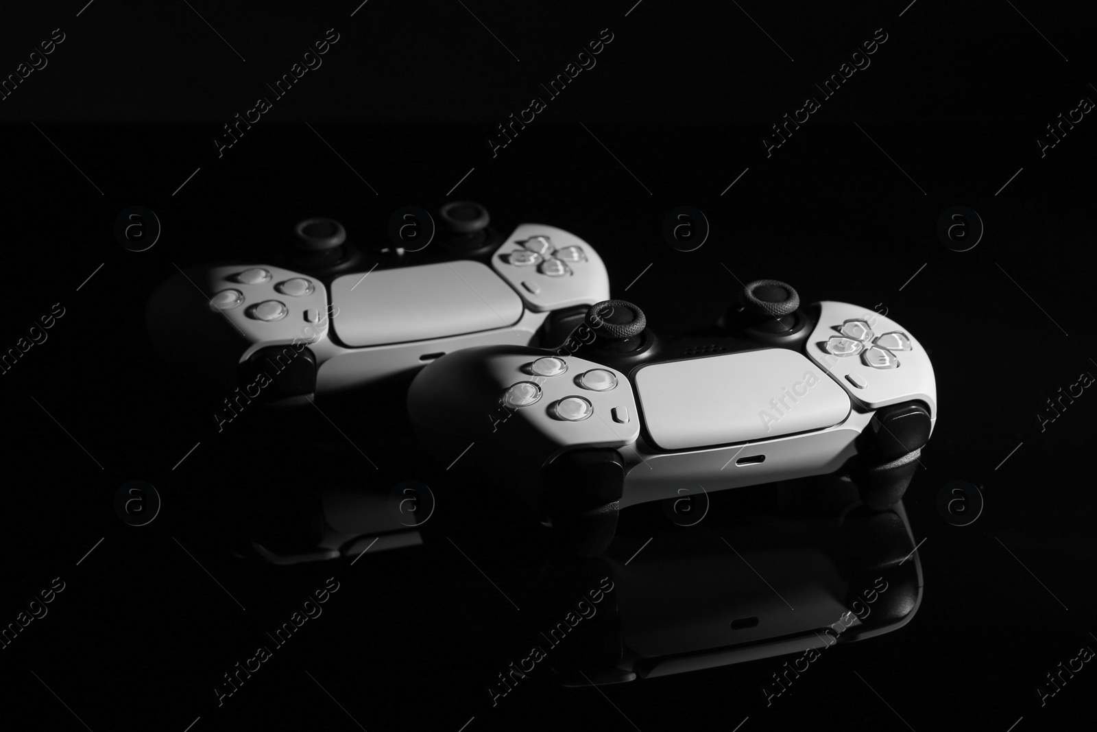 Photo of Wireless game controllers on black mirror surface