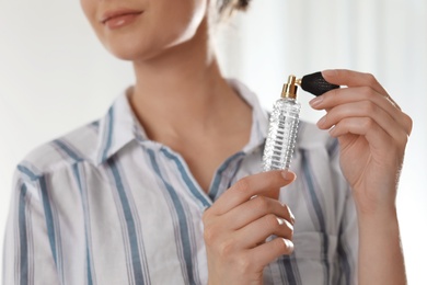 Photo of Young woman applying perfume on neck against blurred background, closeup