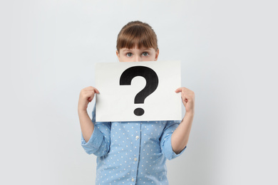 Photo of Girl holding sheet of paper with question mark on white background