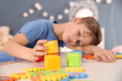 Photo of Little boy with autistic disorder playing at home, closeup of cubes