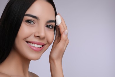 Woman using silkworm cocoon in skin care routine on light grey background. Space for text