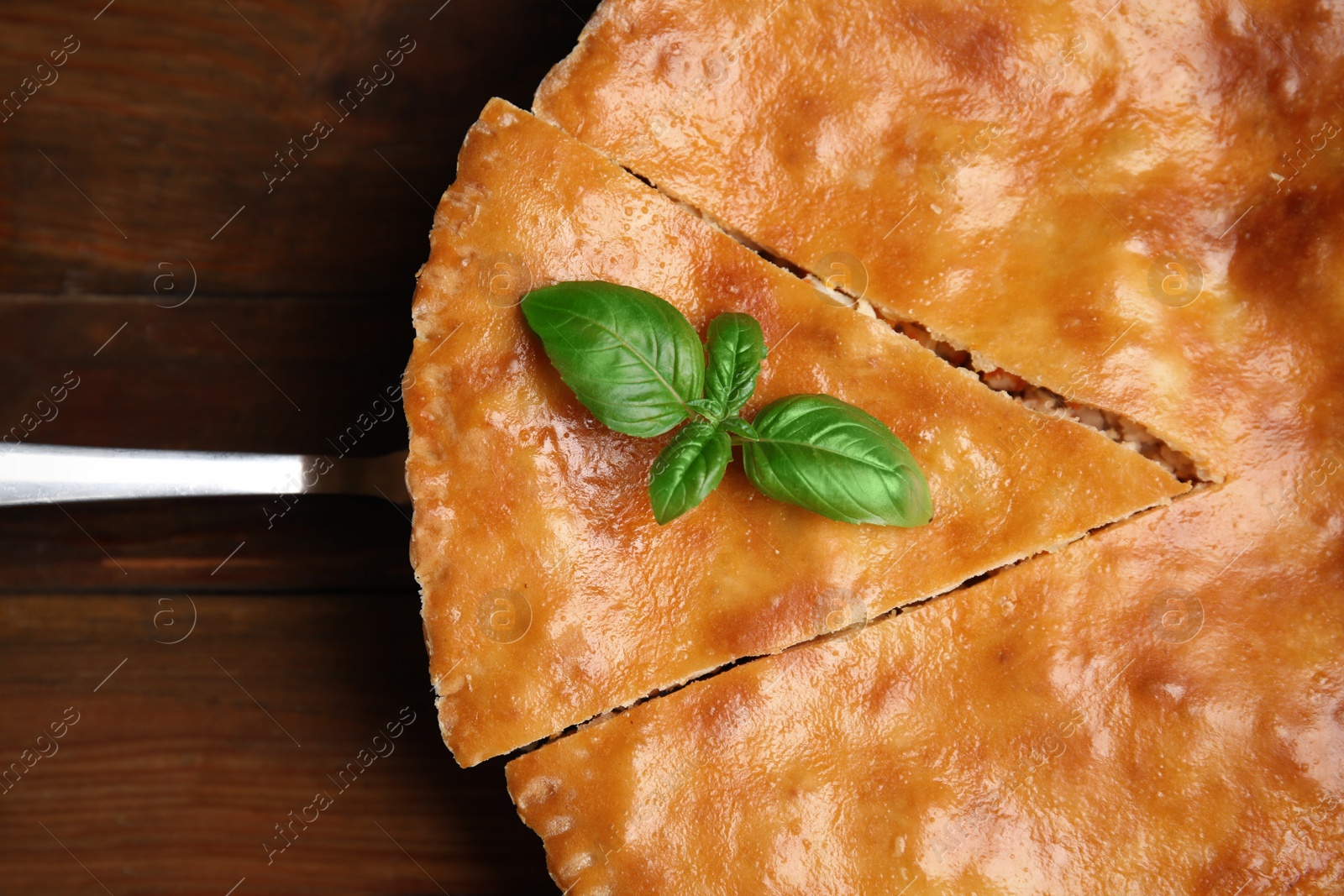 Photo of Delicious pie with meat and basil on wooden table, top view