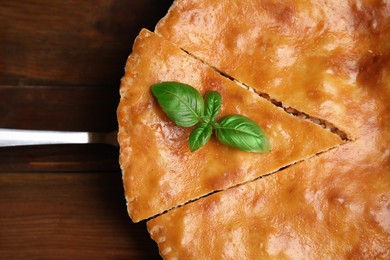 Delicious pie with meat and basil on wooden table, top view