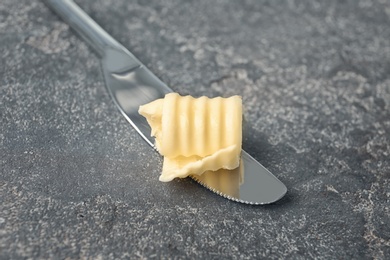 Photo of Knife with fresh butter curl on table