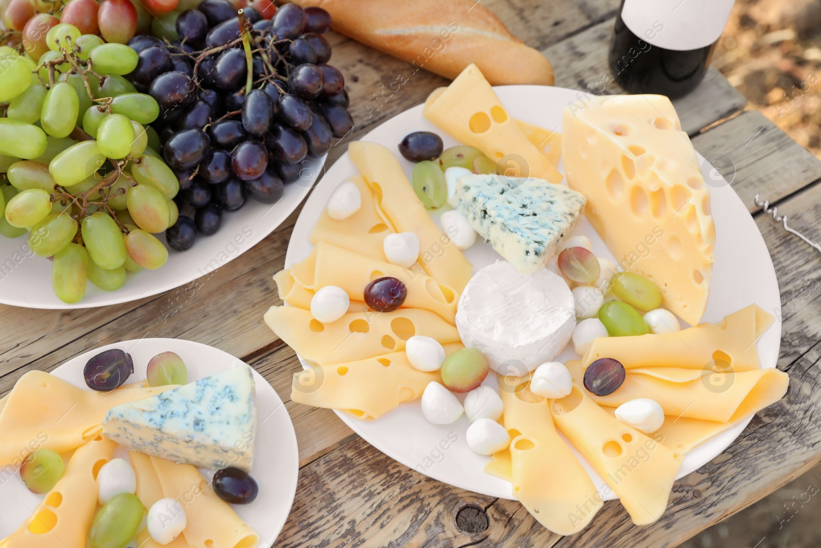 Photo of Cheese and grapes on wooden table. Vineyard picnic