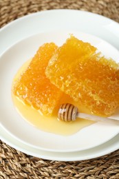 Photo of Natural honeycombs with tasty honey and dipper on wicker mat