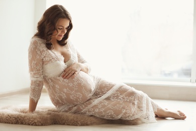 Photo of Young pregnant woman in elegant dress at home