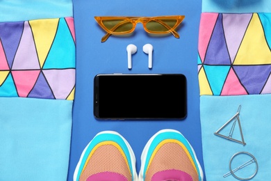 Flat lay composition with stylish sportswear and smartphone on blue background