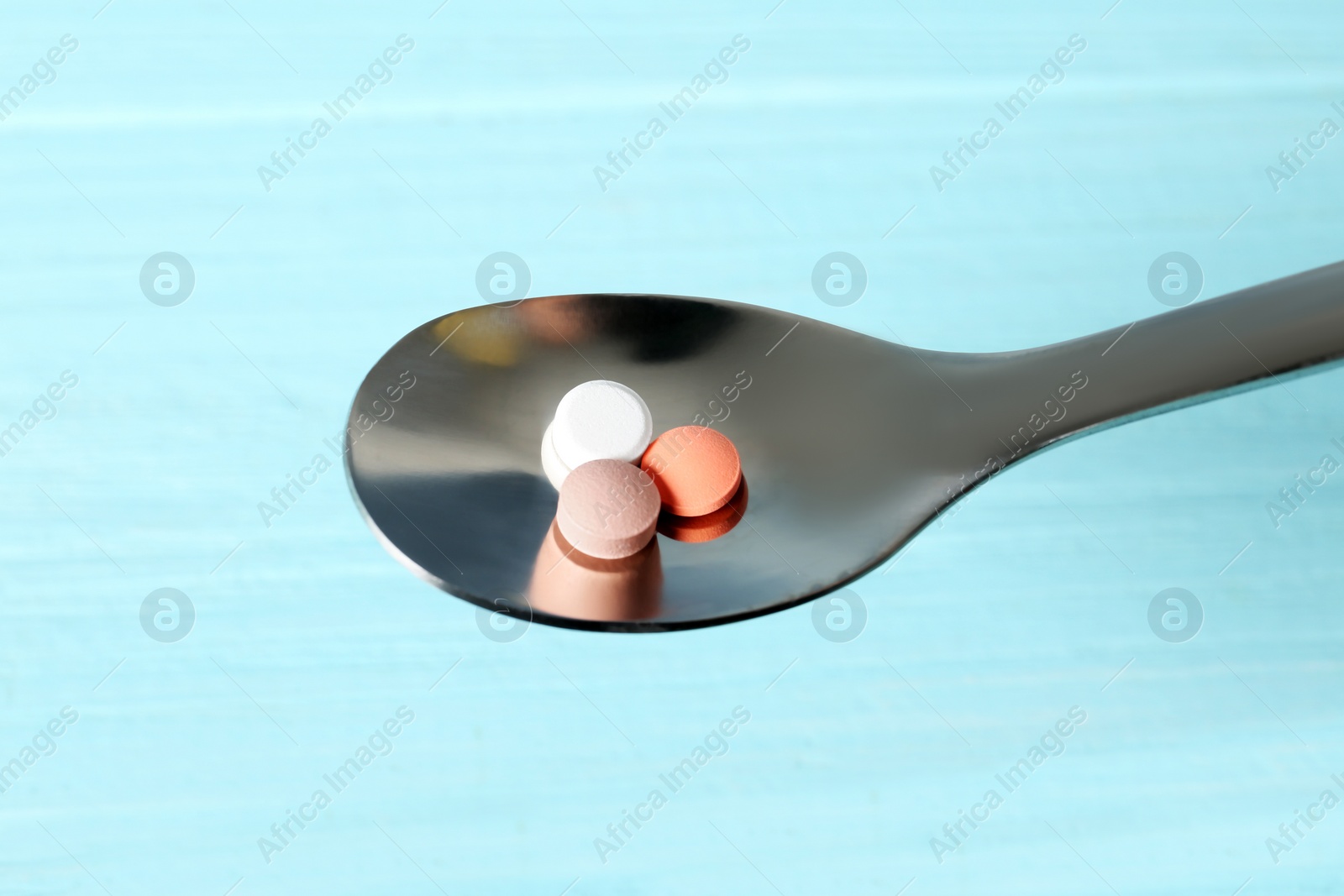 Photo of Spoon with weight loss pills on color background