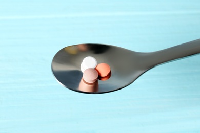 Spoon with weight loss pills on color background