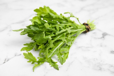 Photo of Fresh arugula on white marble table, closeup