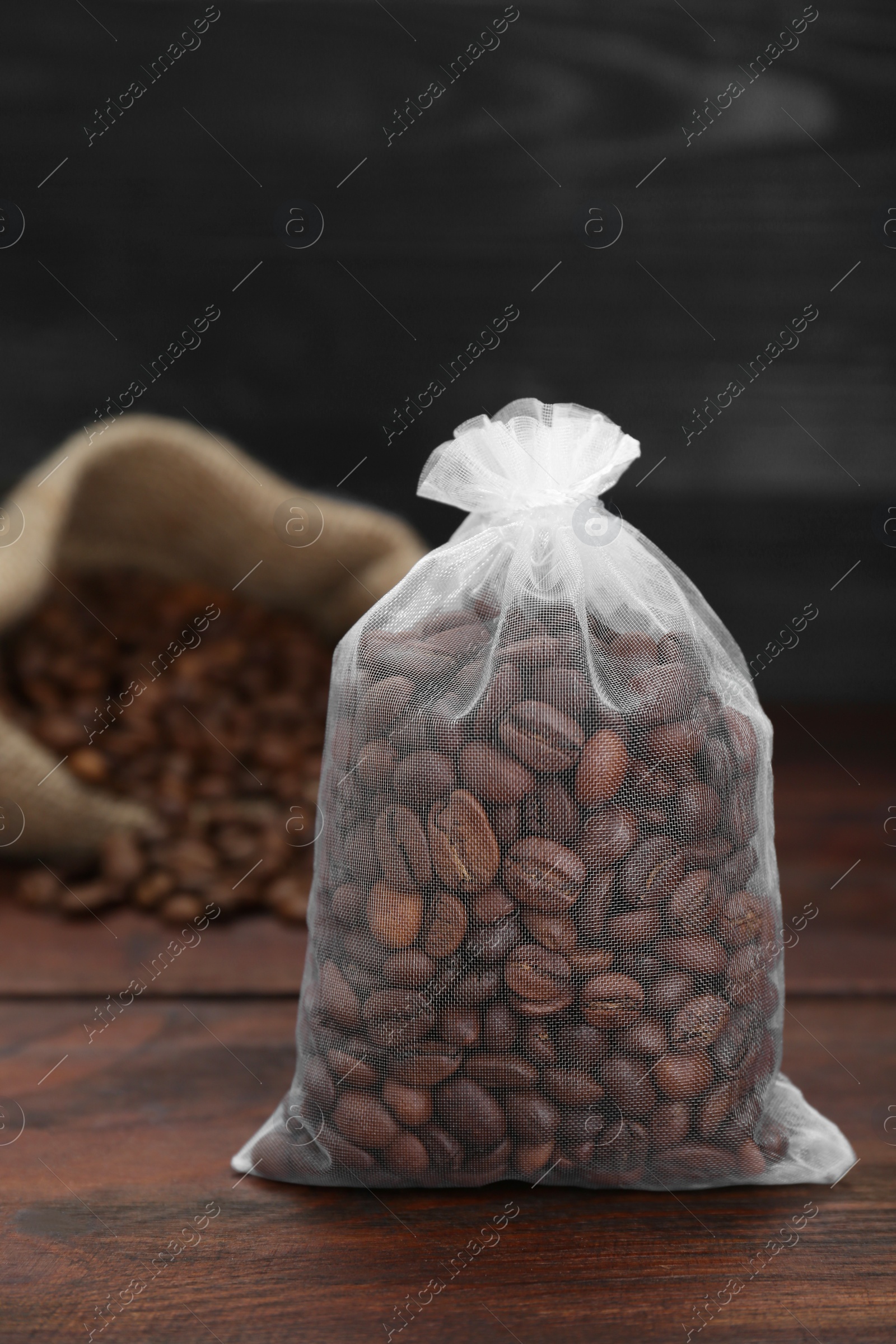 Photo of Scented sachet with coffee beans on wooden table, closeup