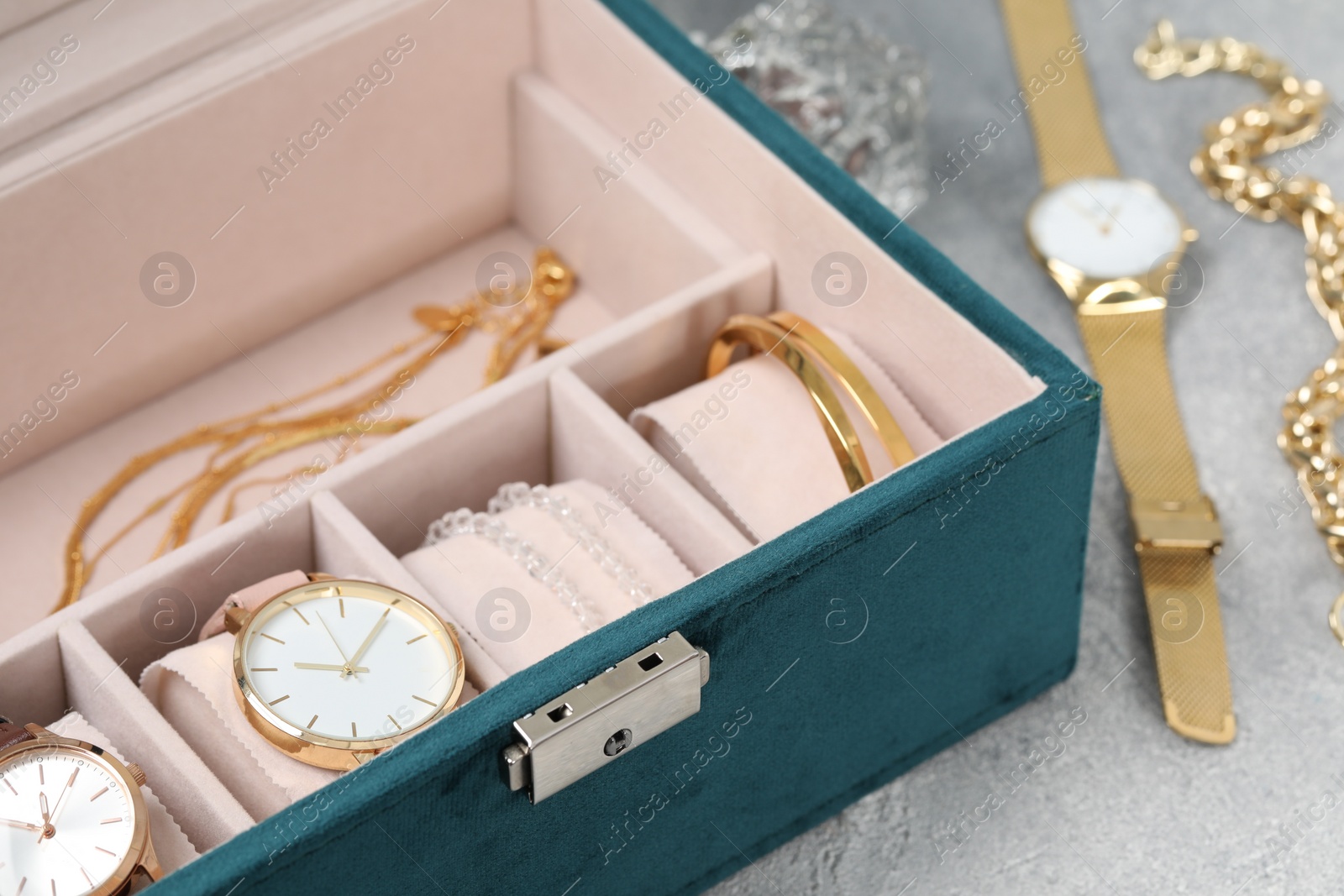 Photo of Jewelry box with many different accessories on light grey table, closeup