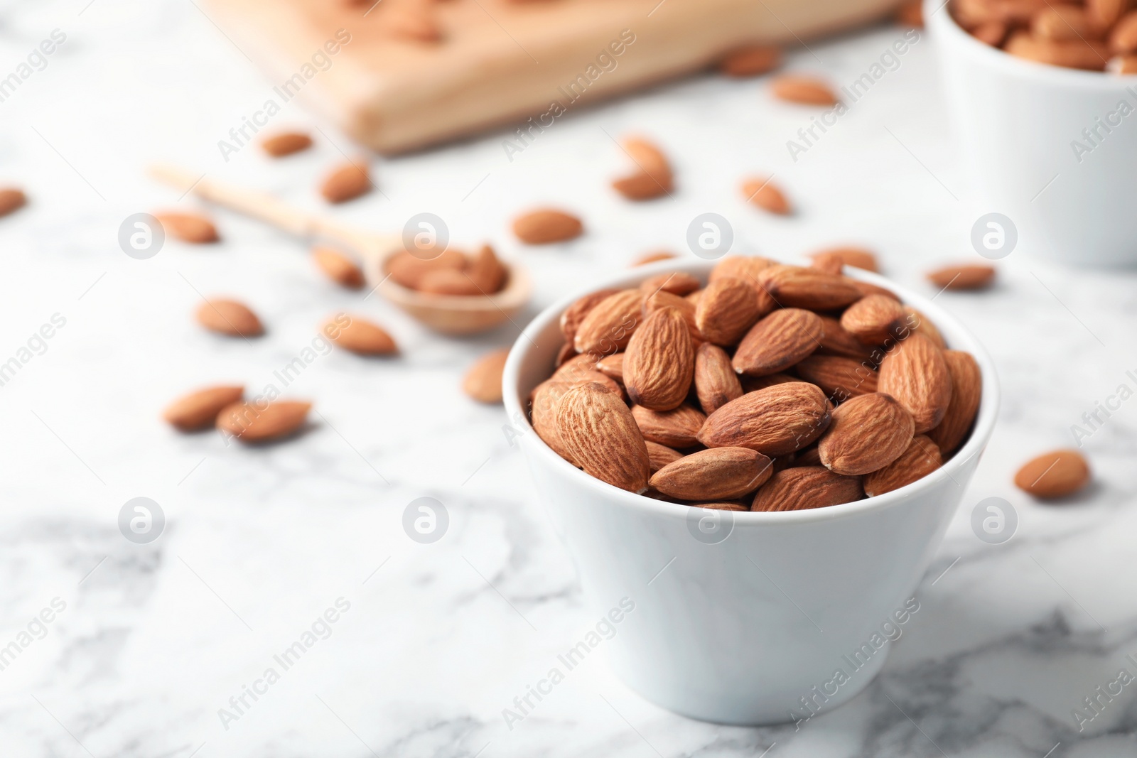 Photo of Tasty organic almond nuts in bowl on table. Space for text