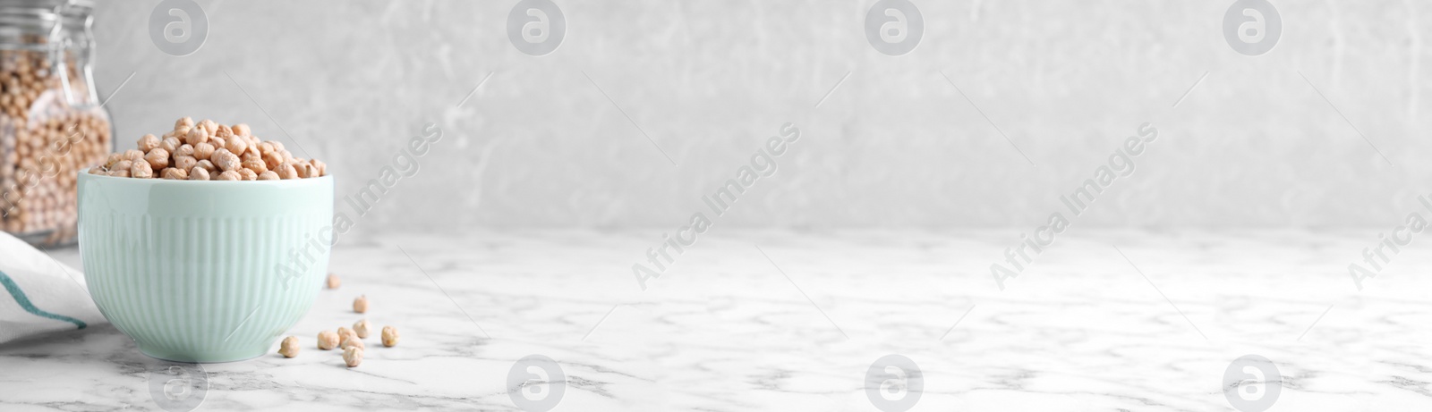 Photo of Chickpeas in bowl on white marble table, space for text