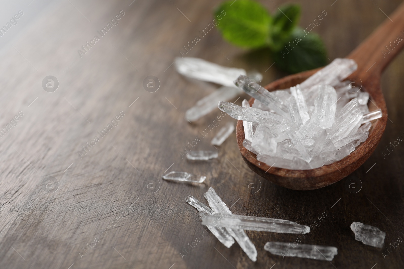 Photo of Menthol crystals on wooden background, closeup. Space for text