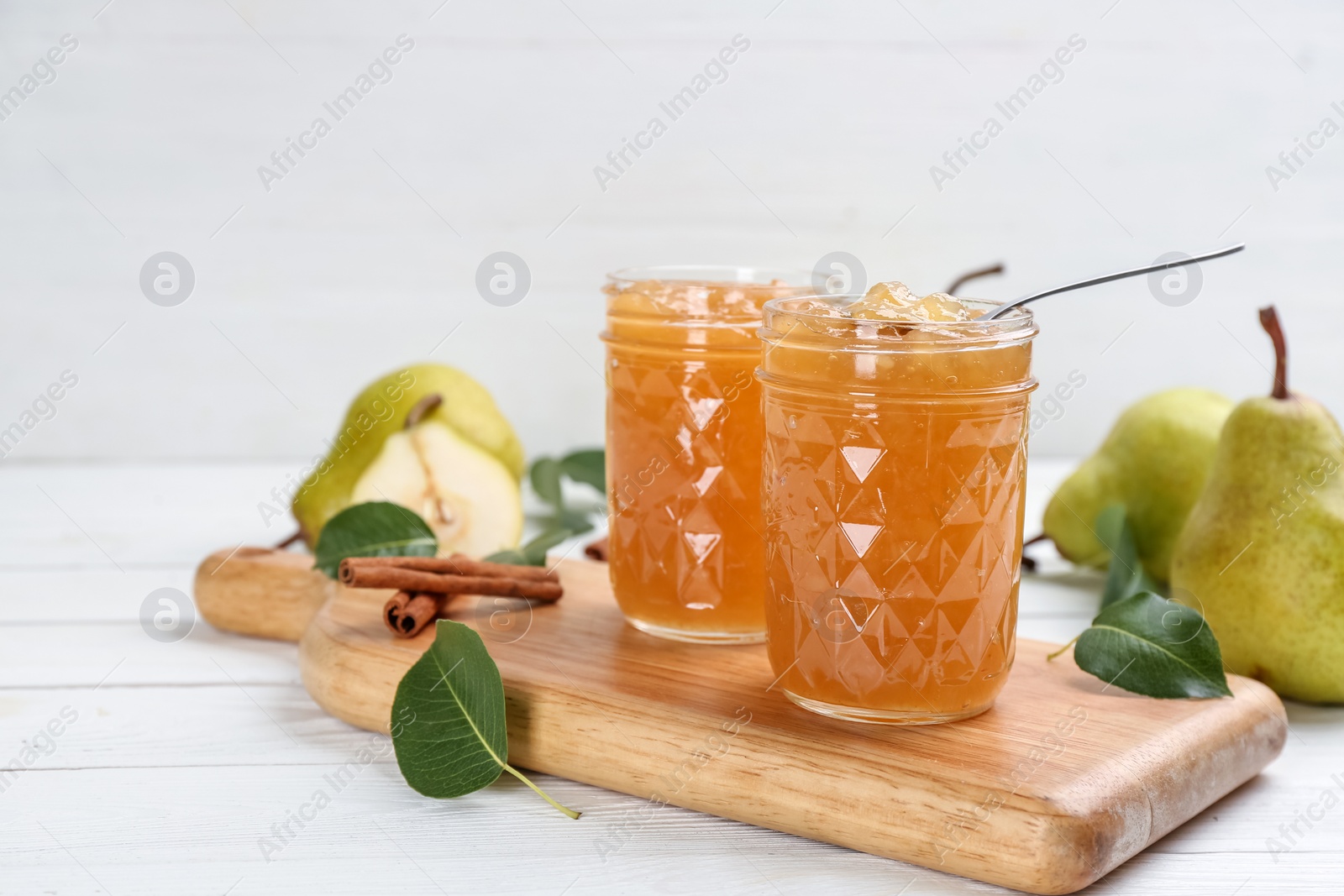 Photo of Delicious pear jam and fresh fruits on white wooden table. Space for text