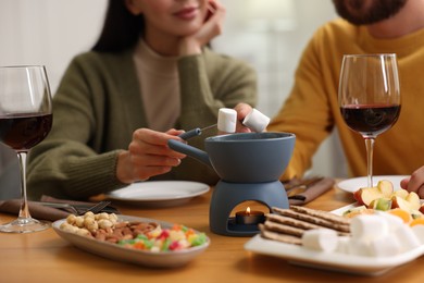 Photo of Couple enjoying fondue during romantic date indoors, closeup