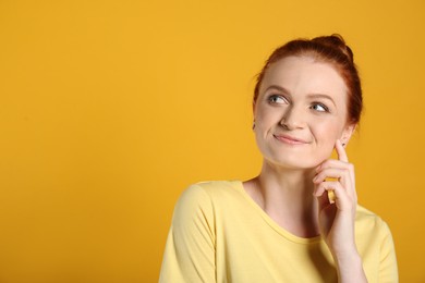 Portrait of happy red haired woman on yellow background, space for text