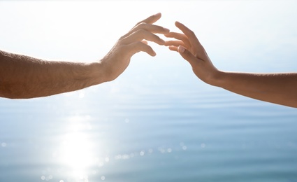 Photo of Man and woman reaching hands to each other at sunset, closeup. Nature healing power