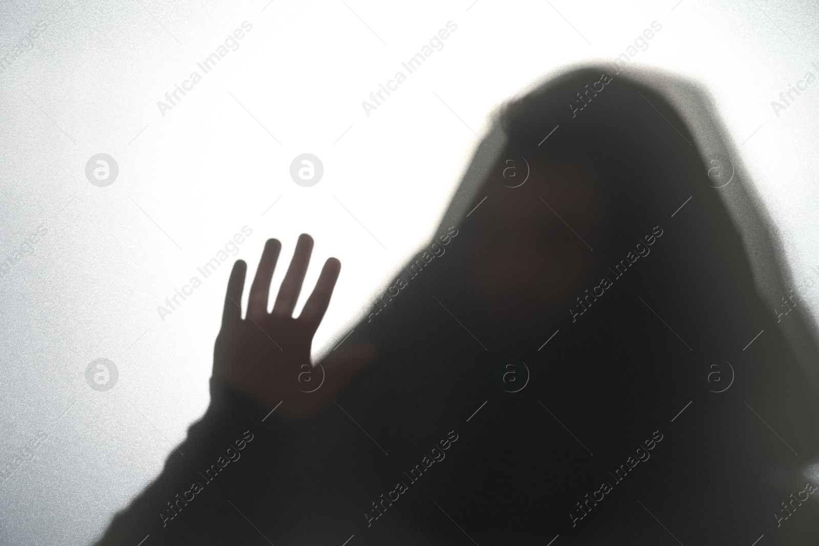 Photo of Silhouette of ghost behind glass against white background