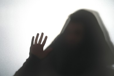 Silhouette of ghost behind glass against white background
