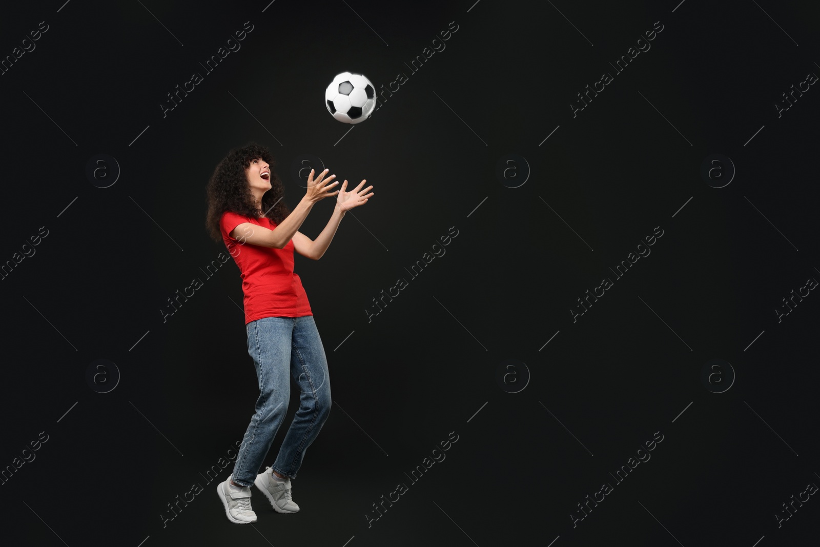 Photo of Happy fan playing with soccer ball on black background, space for text