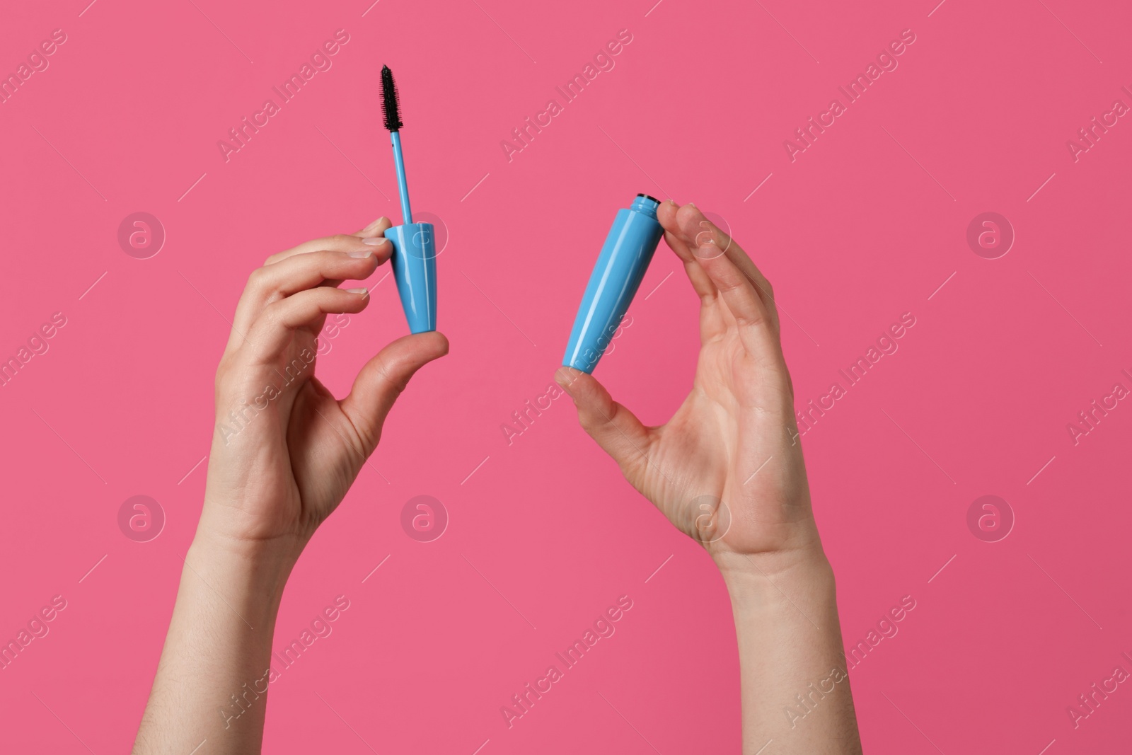 Photo of Woman holding mascara for eyelashes on bright pink, closeup