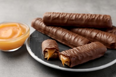 Sweet tasty chocolate bars with caramel on grey table